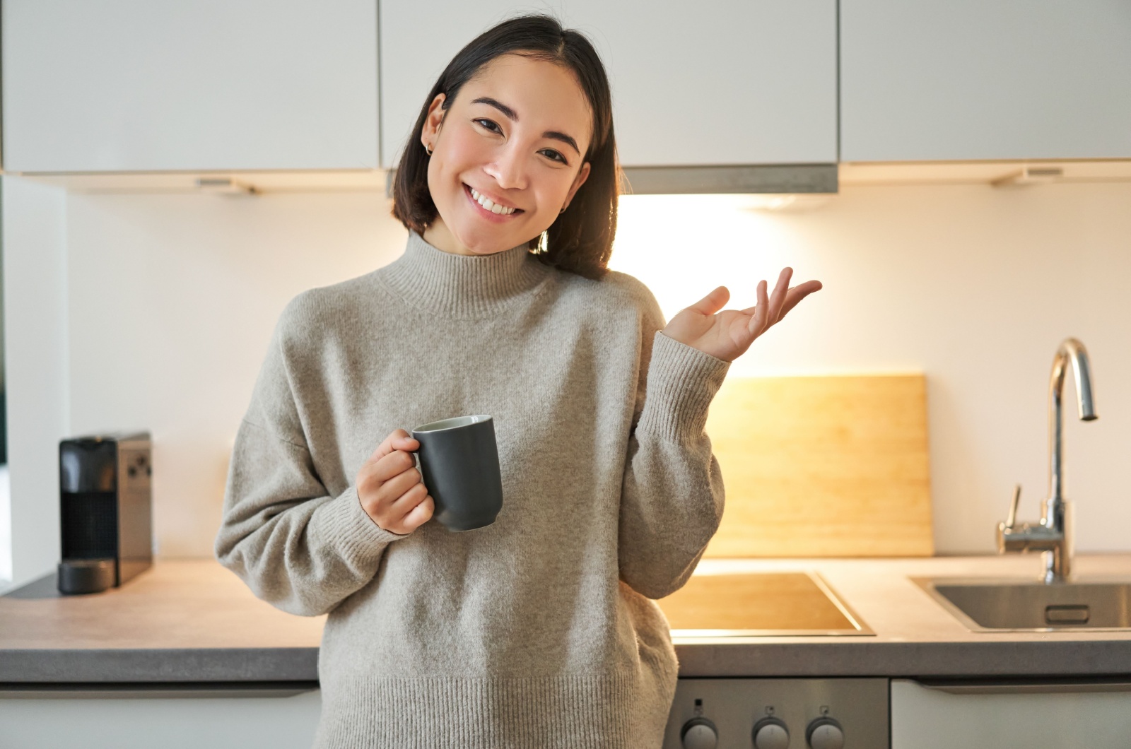Frau haelt einen Kaffee in der Kueche