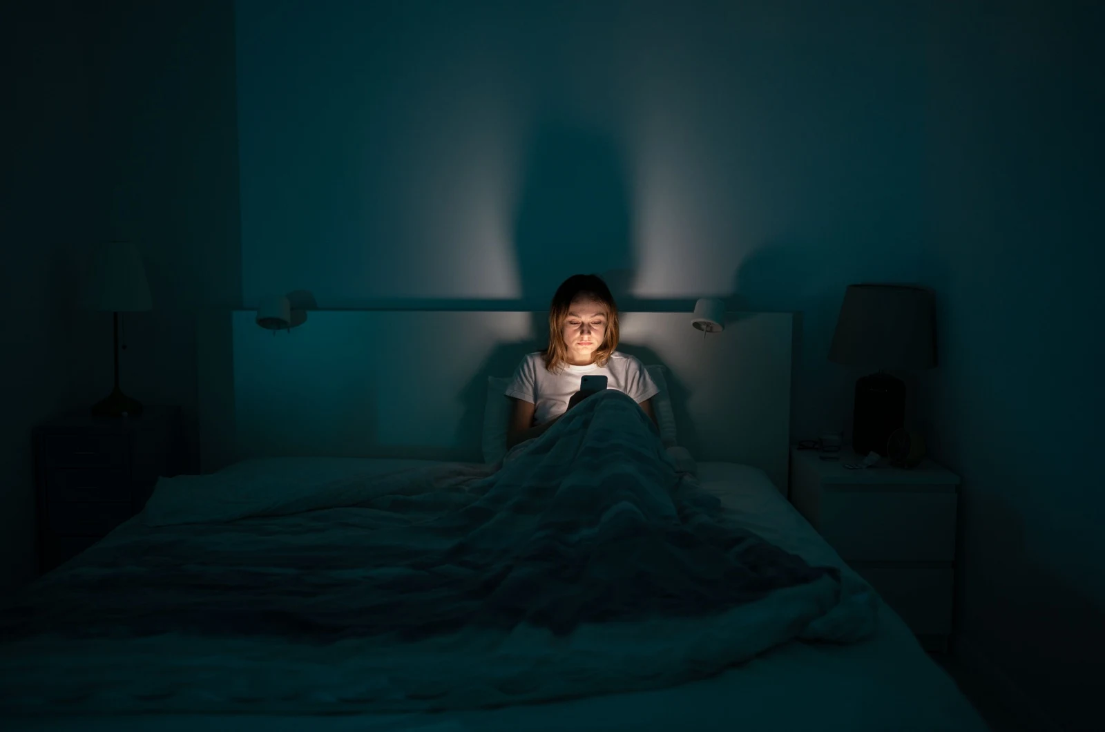 Frau im Bett tippt auf dem Telefon