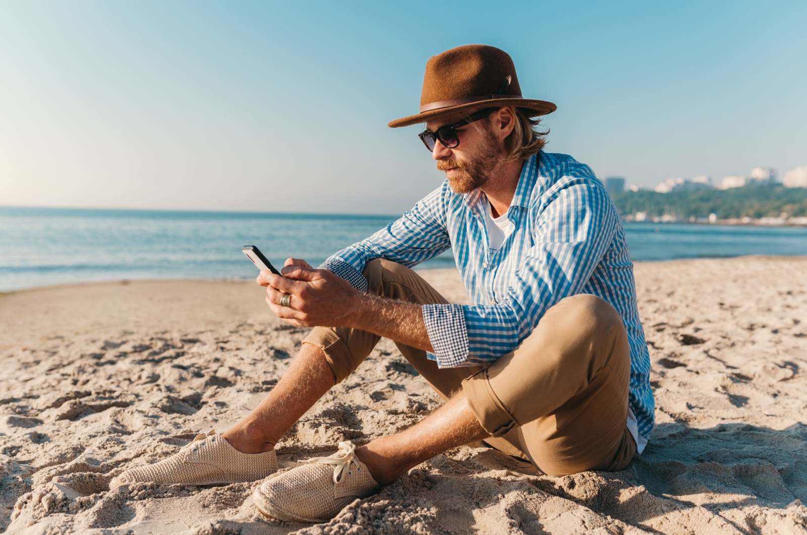 Mann haelt ein Telefon im Urlaub