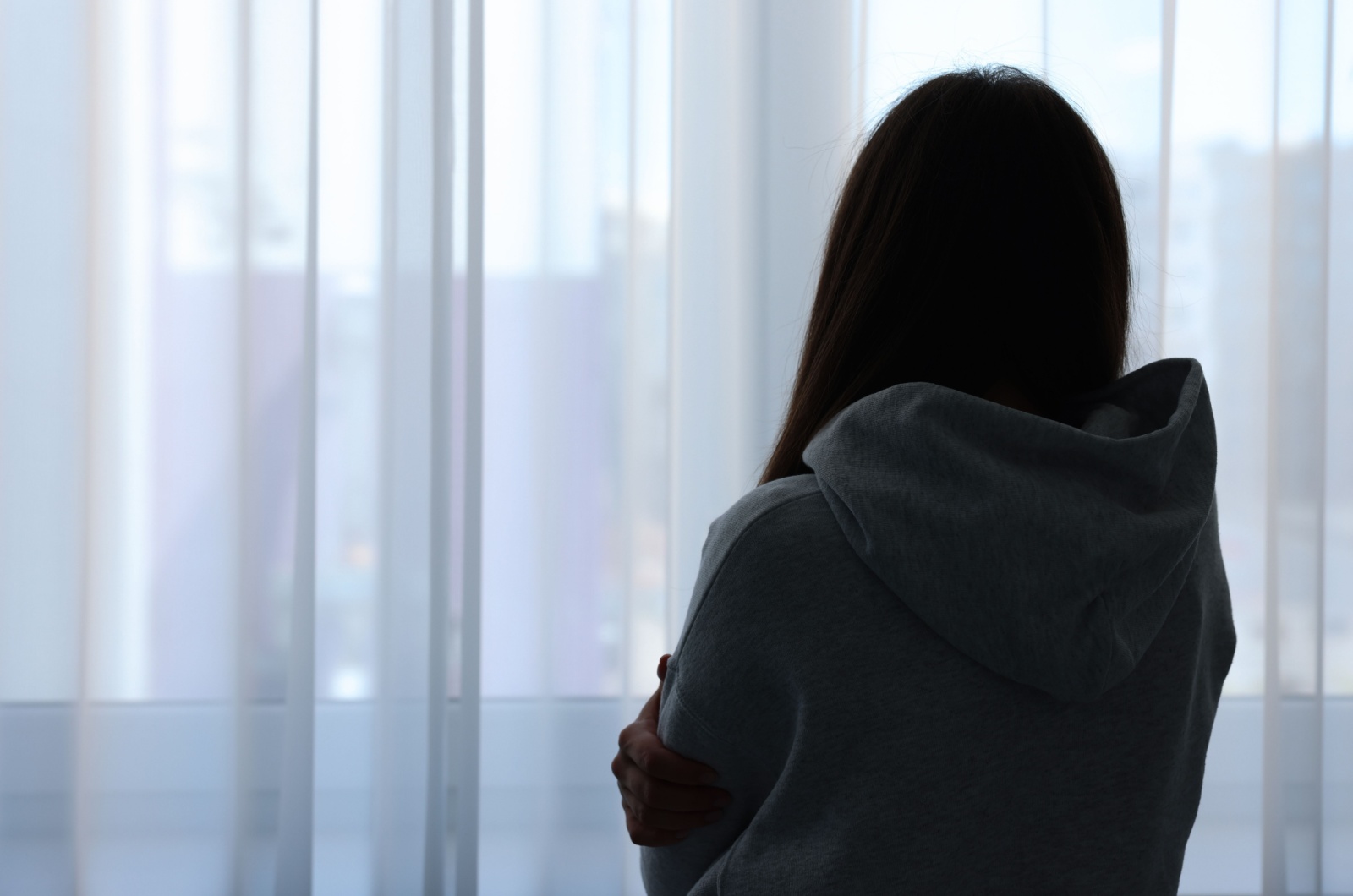 traurige Frau beobachtet durch Fenster