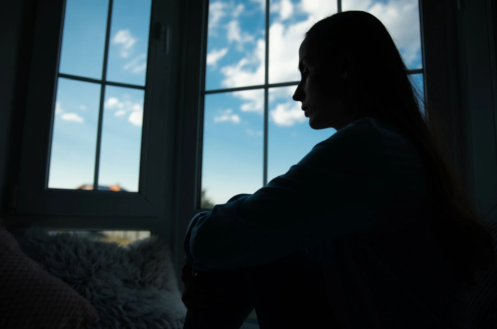 traurige Frau sitzt am Fenster