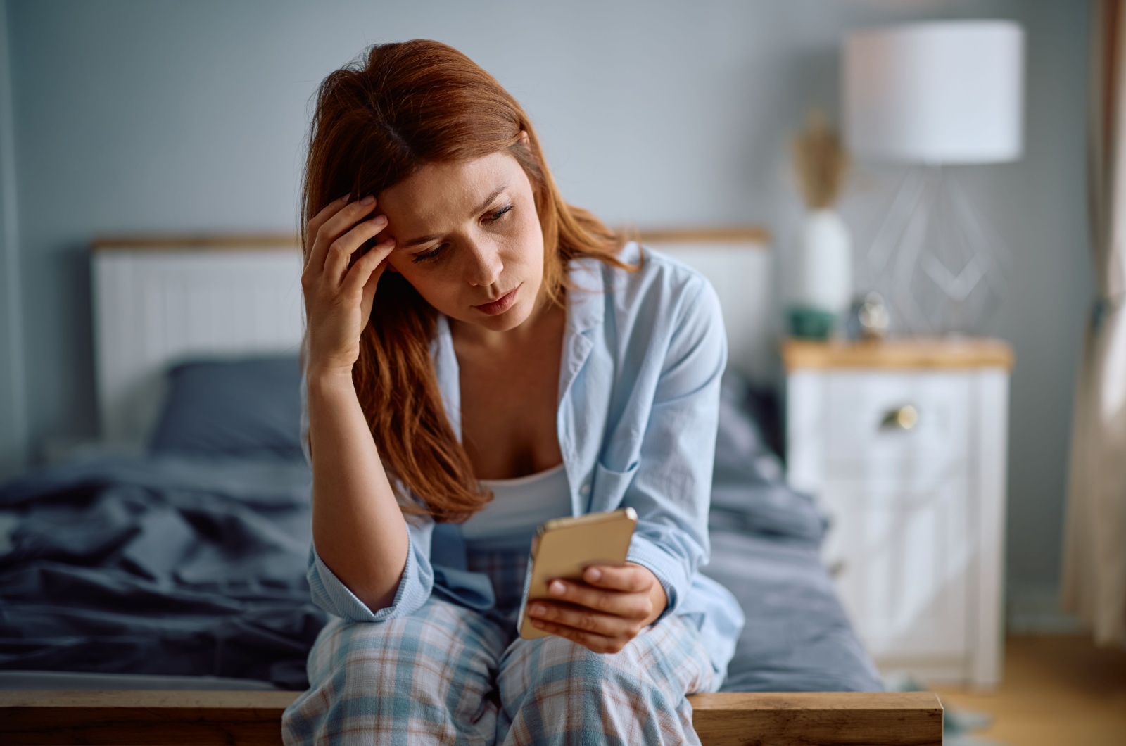 frau liest nachricht am bett