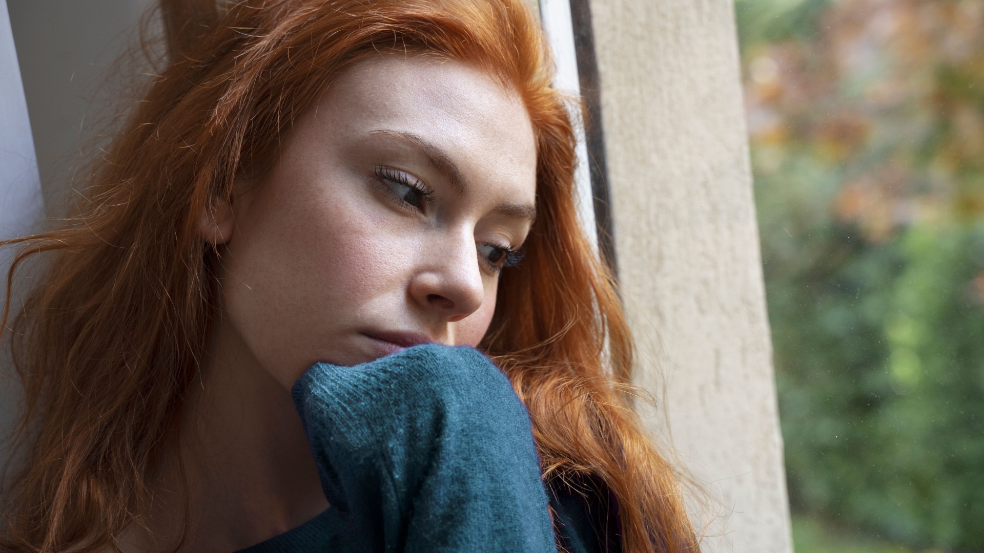 traurige frau schaut durch fenster