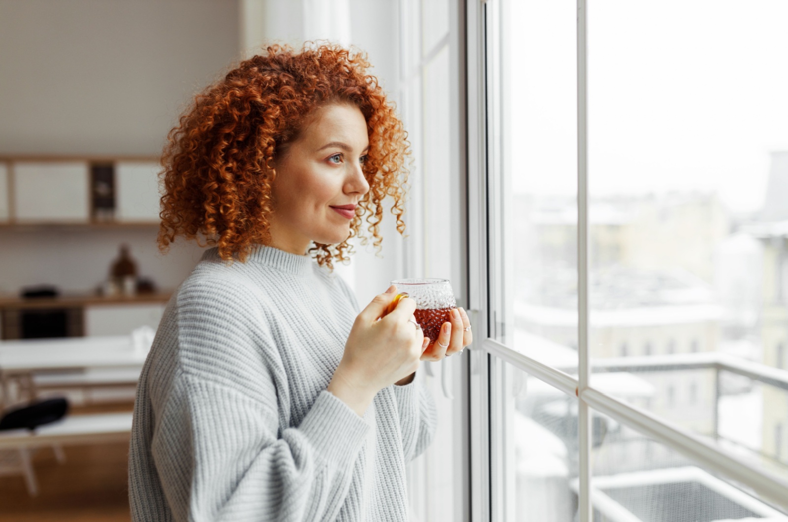 frau schaut aus fenster mit kaffee
