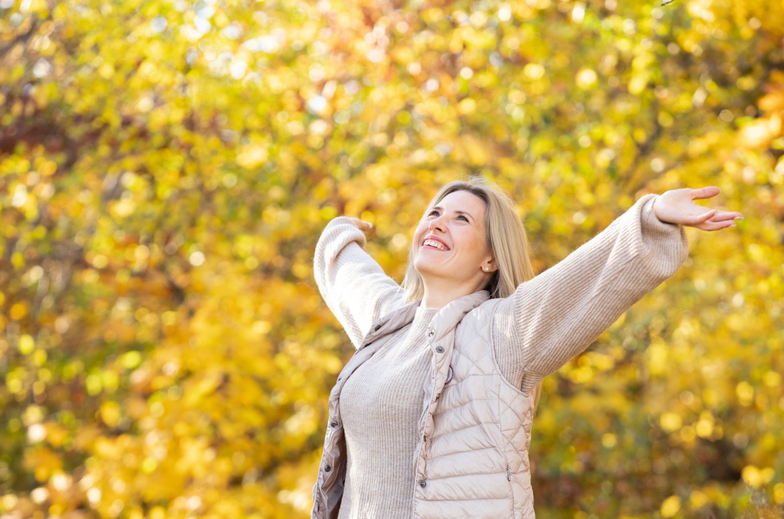 frau streckt arme aus im herbst