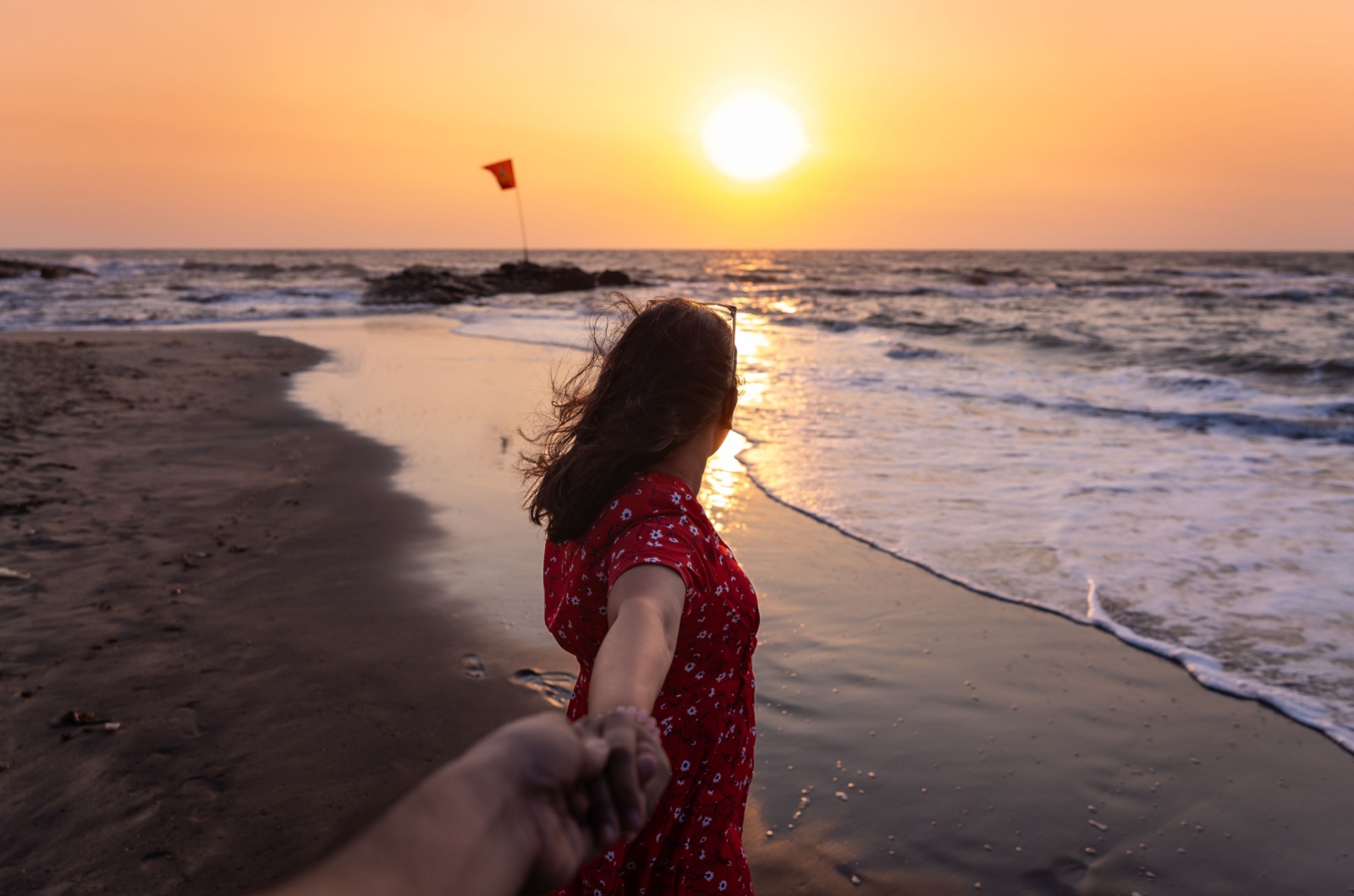 frau fuehrt mann an strand