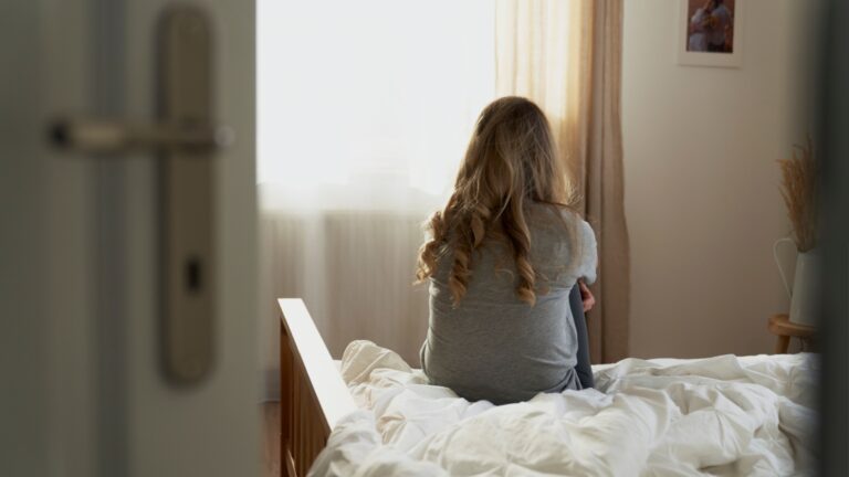 frau sitzt alleine im schlafzimmer