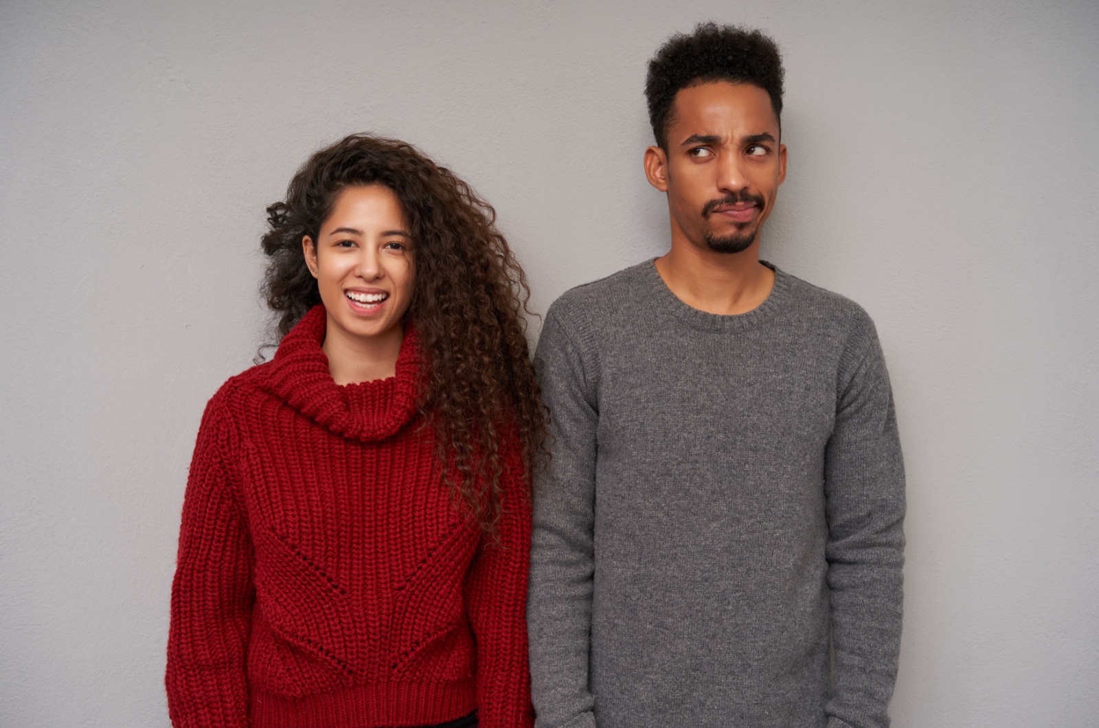 glueckliche frau steht neben frustriertem mann