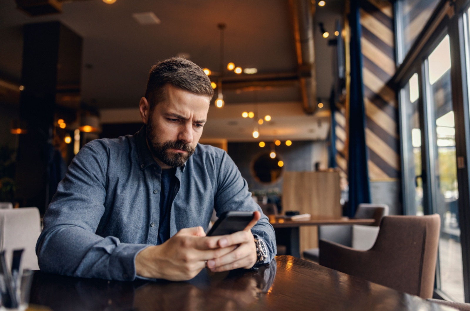 mann schreibt sms im cafe