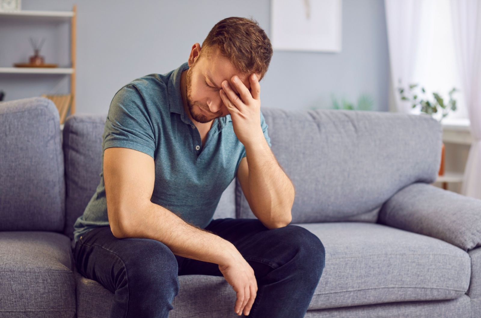 mann sitzt auf sofa und gruebelt