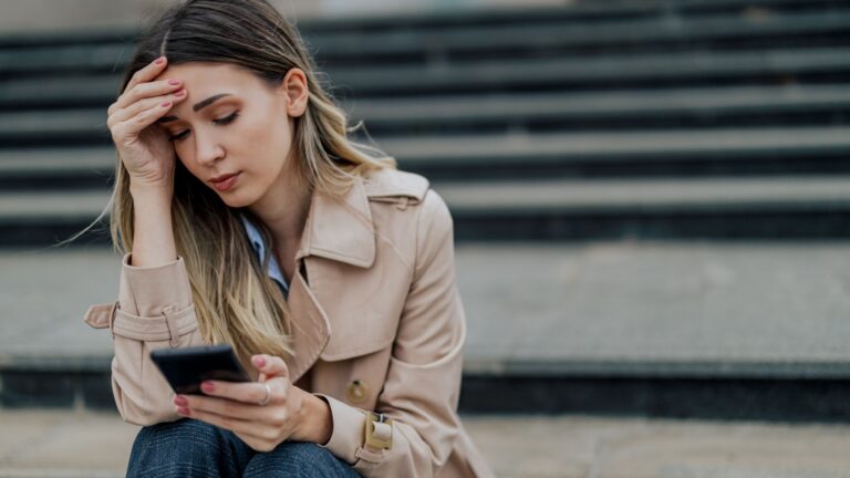 traurige frau mit handy in der hand