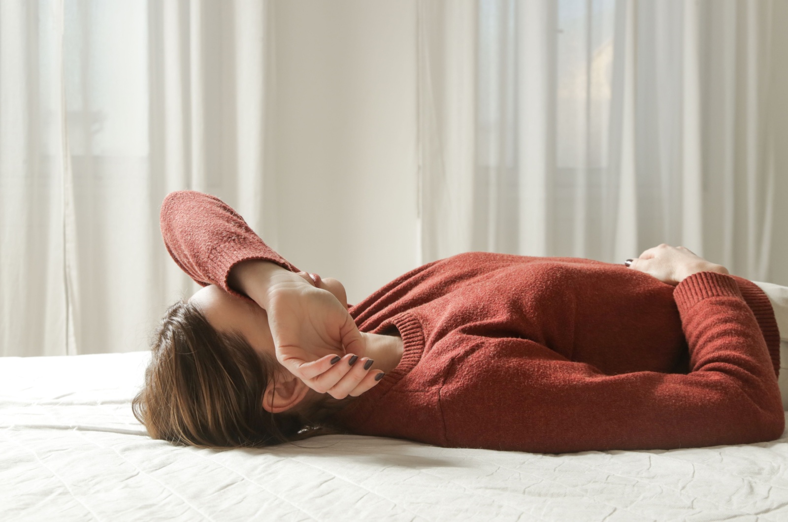 frau liegt muede auf bett
