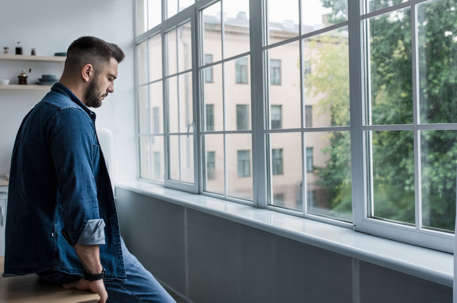 mann sitzt neben fenster