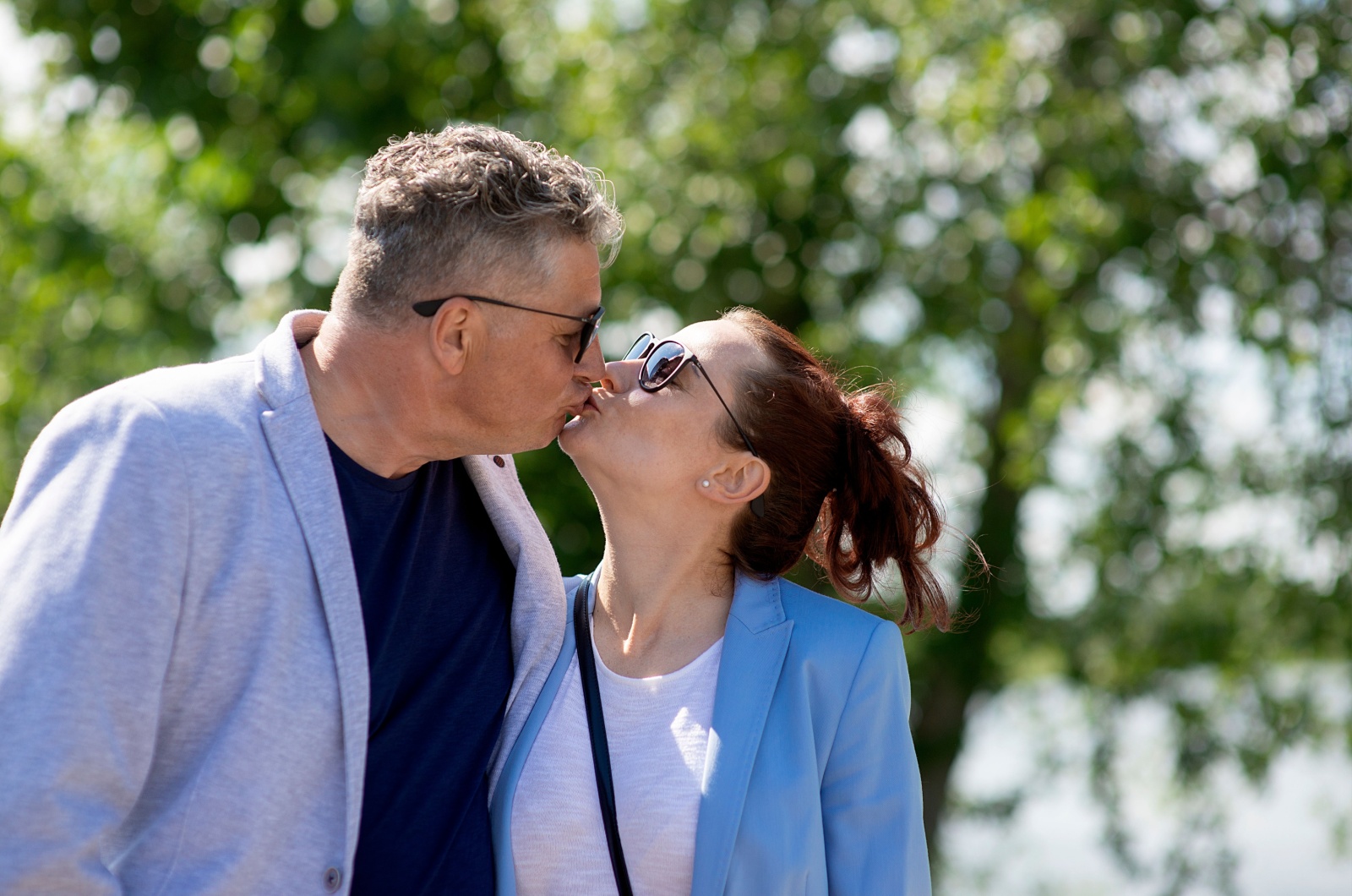 aelterer mann und juengere frau kuessen sich