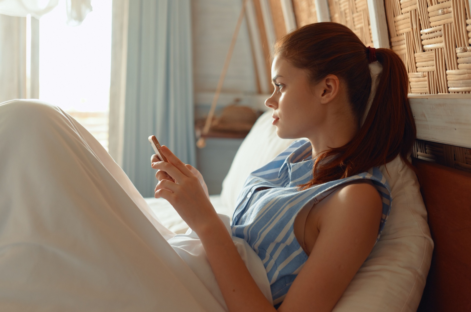 frau liegt im bett mit handy in der hand