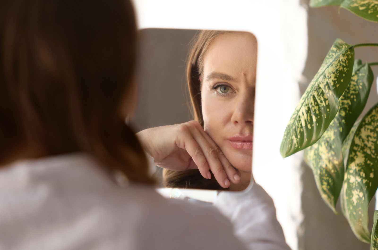 frau sieht sich im spiegel traurig an