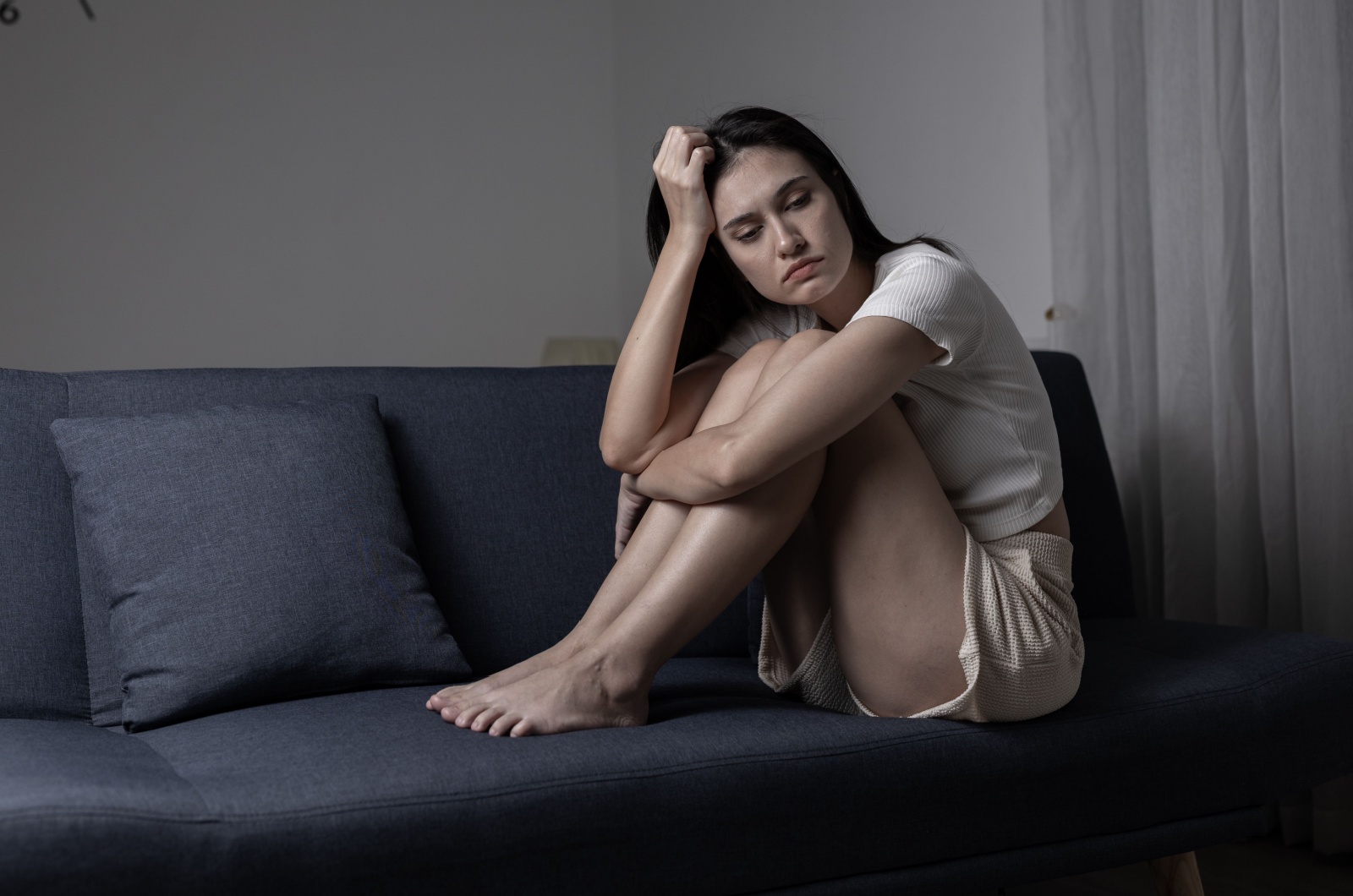 frau sitzt auf sofa und ist traurig