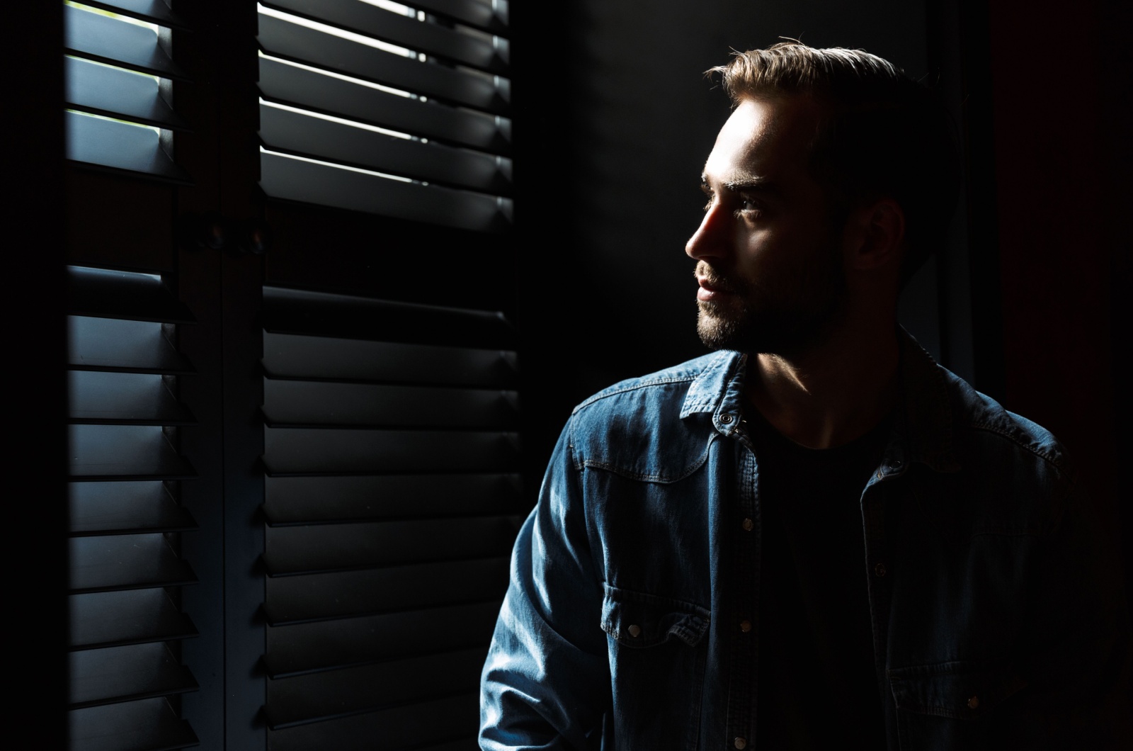 mann im schatten vor fenster