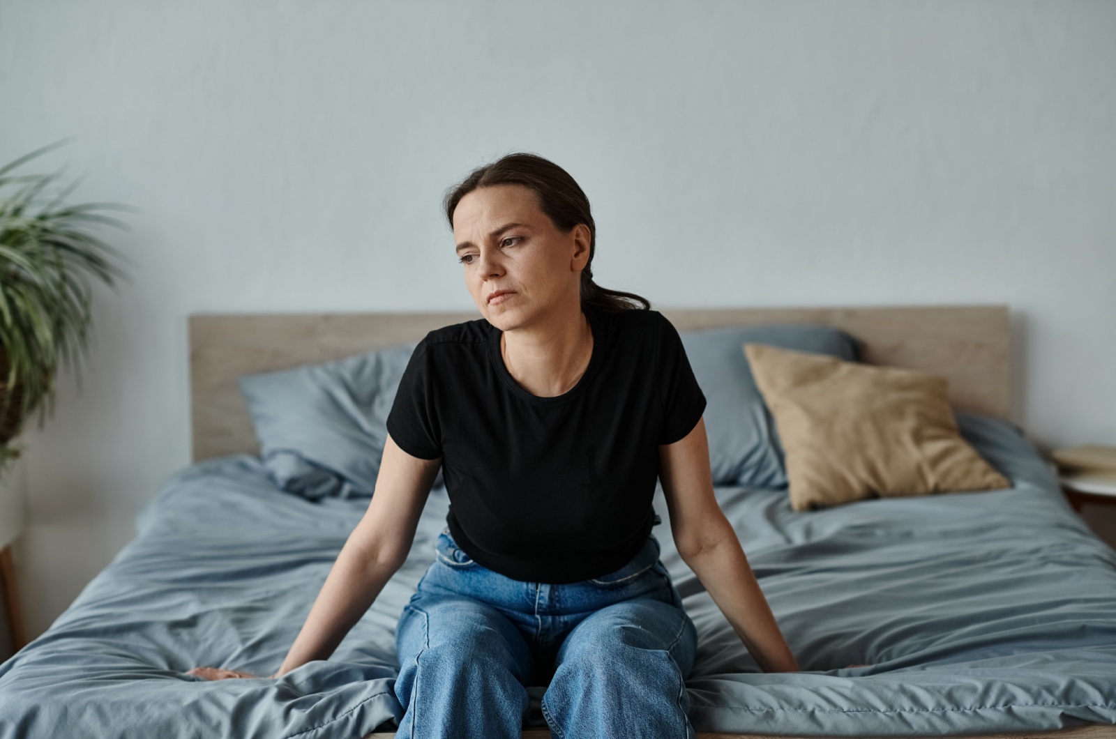 traurige frau sitzt alleine auf ihrem bett