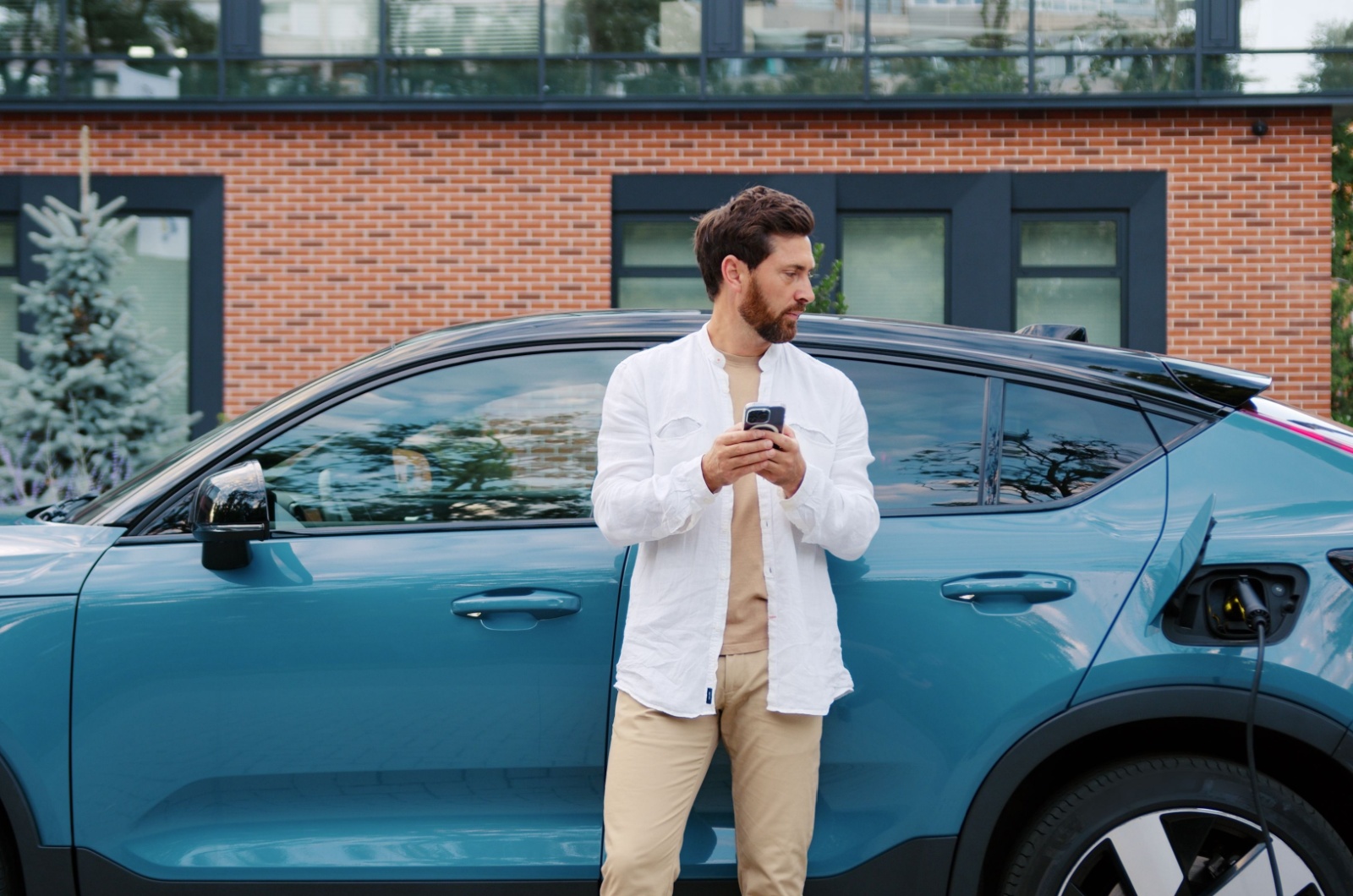 mann vor auto mit handy