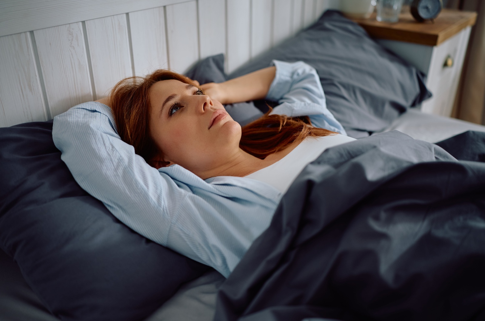frau liegt im bett und gruebelt