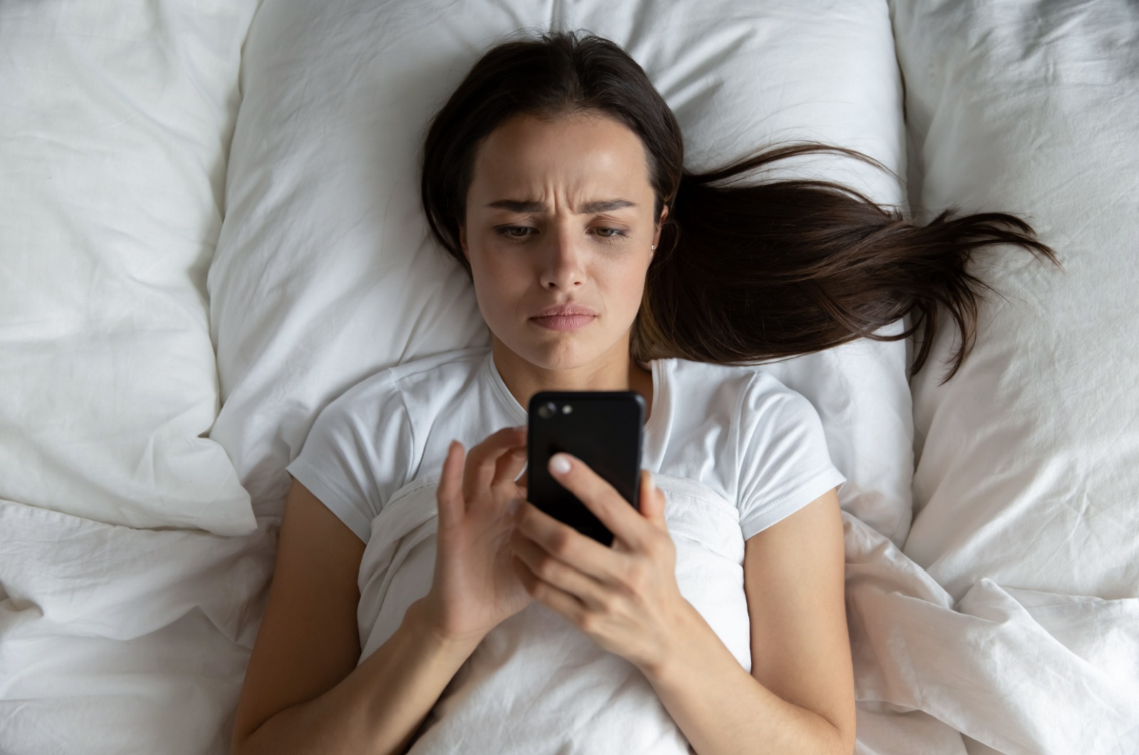 frau mit handy im bett