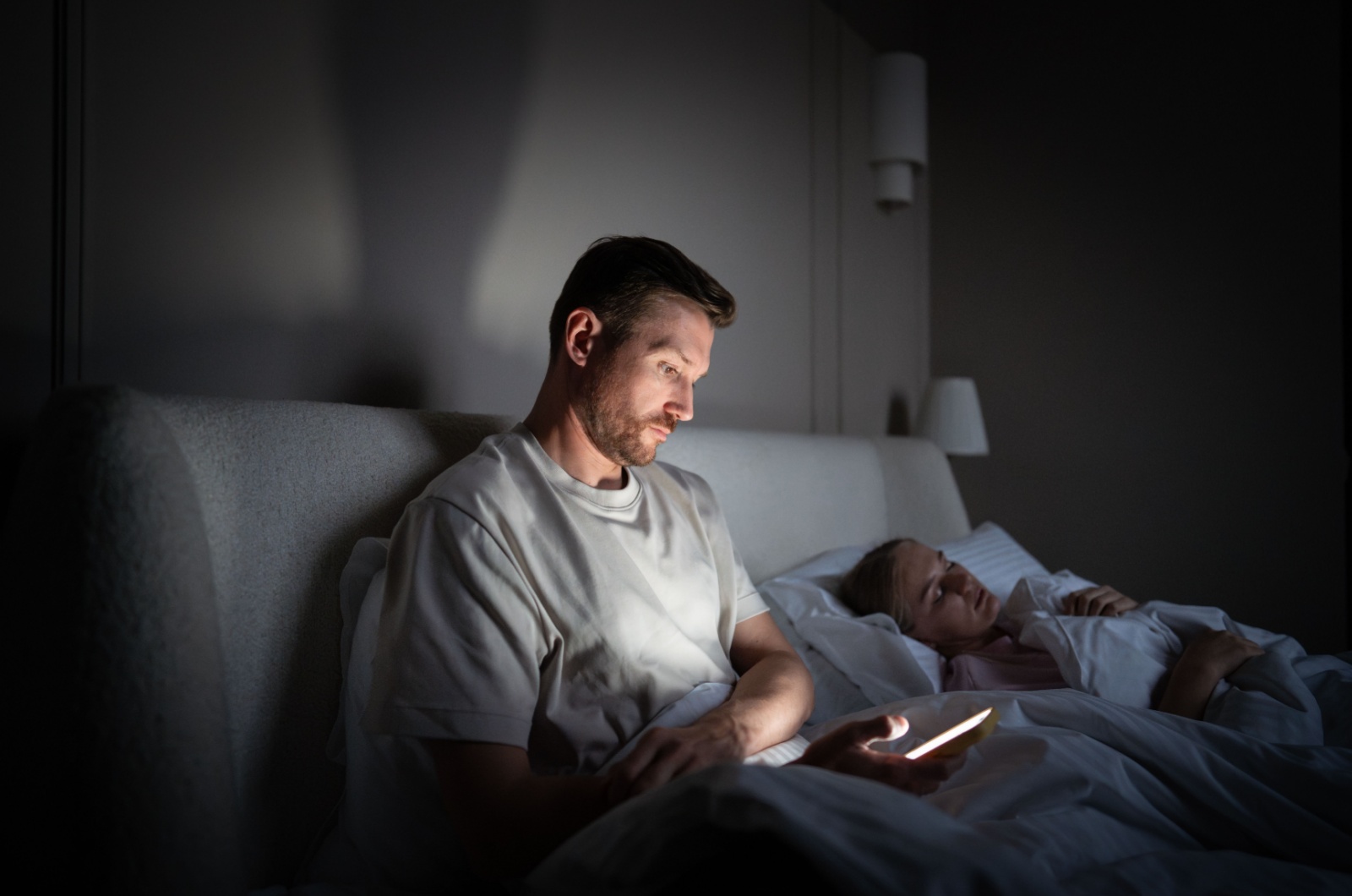 mann mit handy im bett