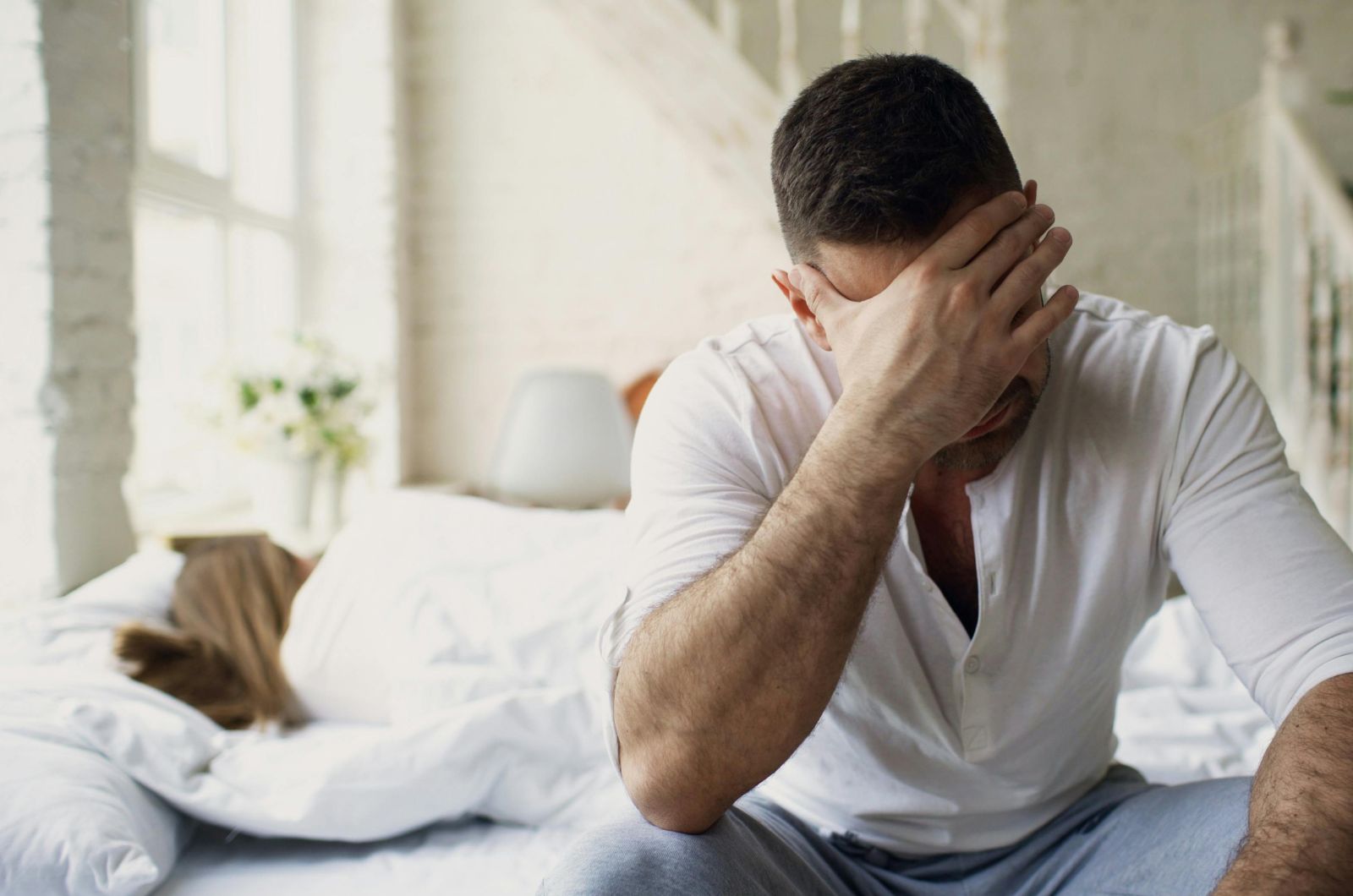 trauriger mann neben frau im bett